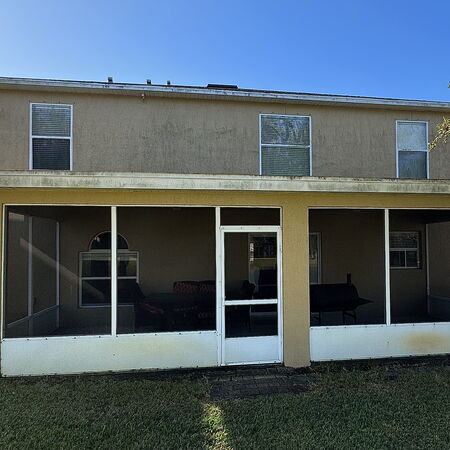 Dirty yellow stucco two story house before soft washing