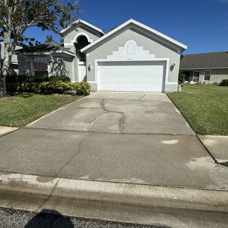 Clean driveway after pressure washing gray house